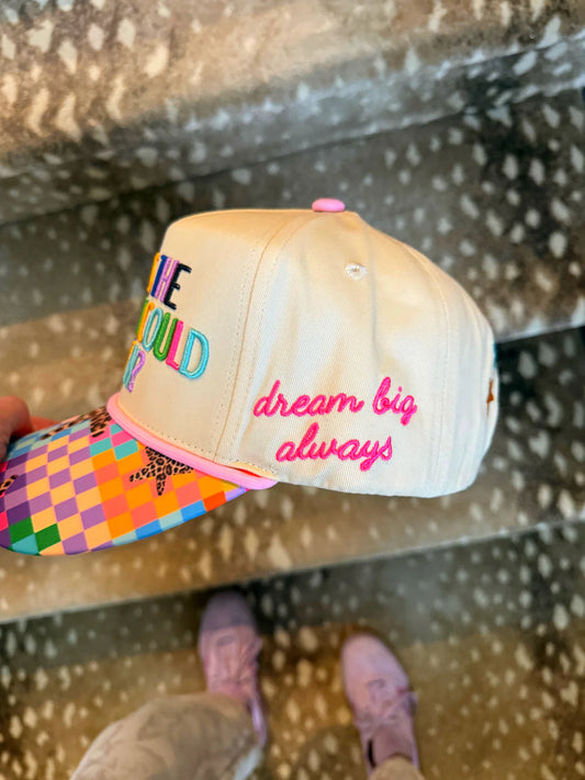 Beige cap with colorful text and a checkered bill on a textured surface