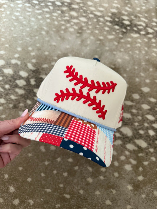 Small fabric baseball with red stitching held against a textured surface