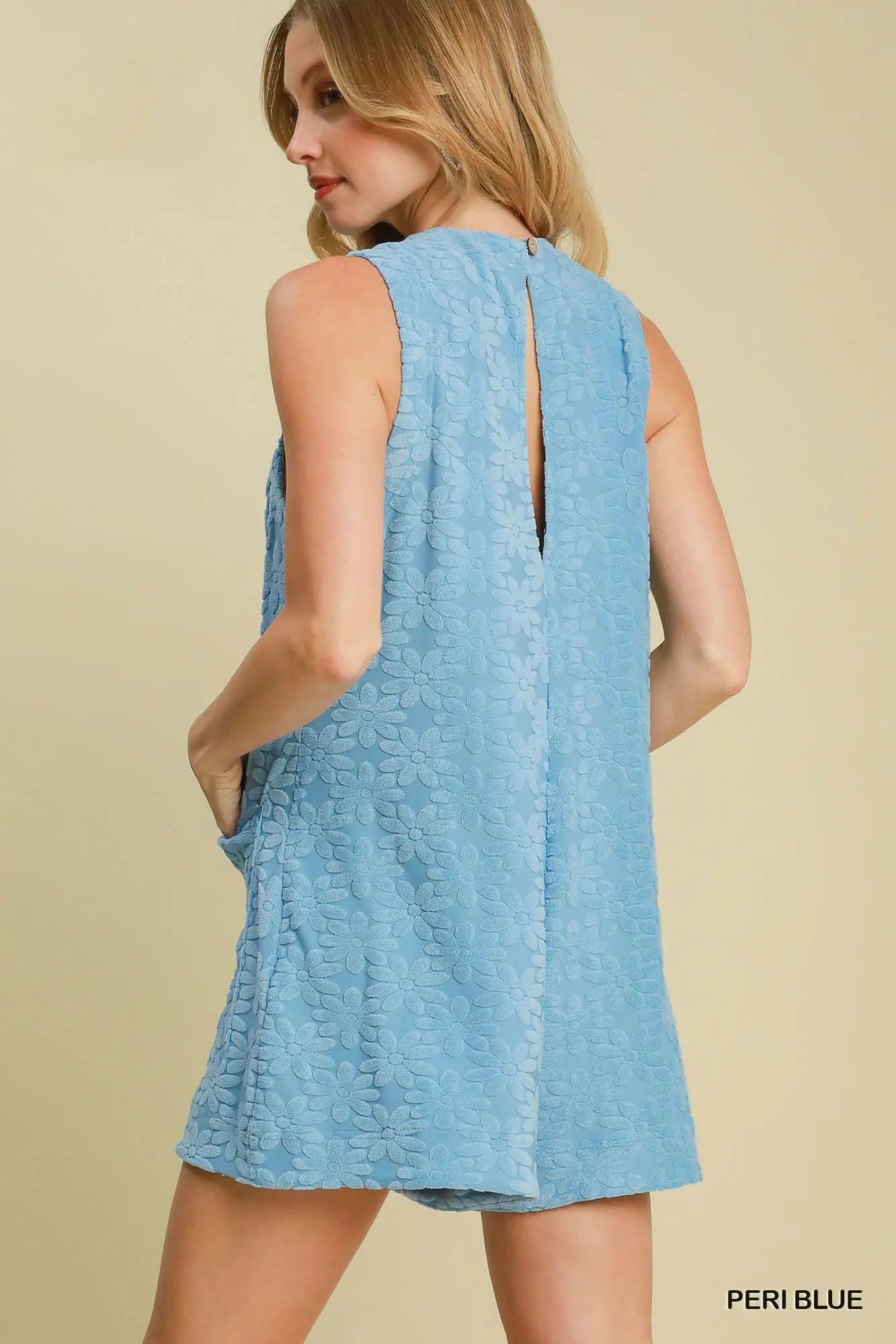 Woman wearing a light blue sleeveless dress on a beige background
