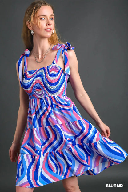 Woman wearing a colorful dress with a blue, pink, and red pattern on a gray background