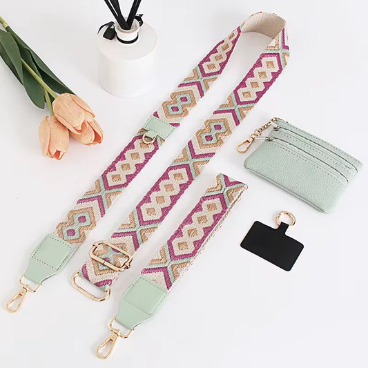 Patterned bag strap, light green wallet, and black keychain on a white surface with flowers.