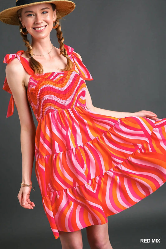Woman wearing a colorful dress with a red and orange pattern on a gray background