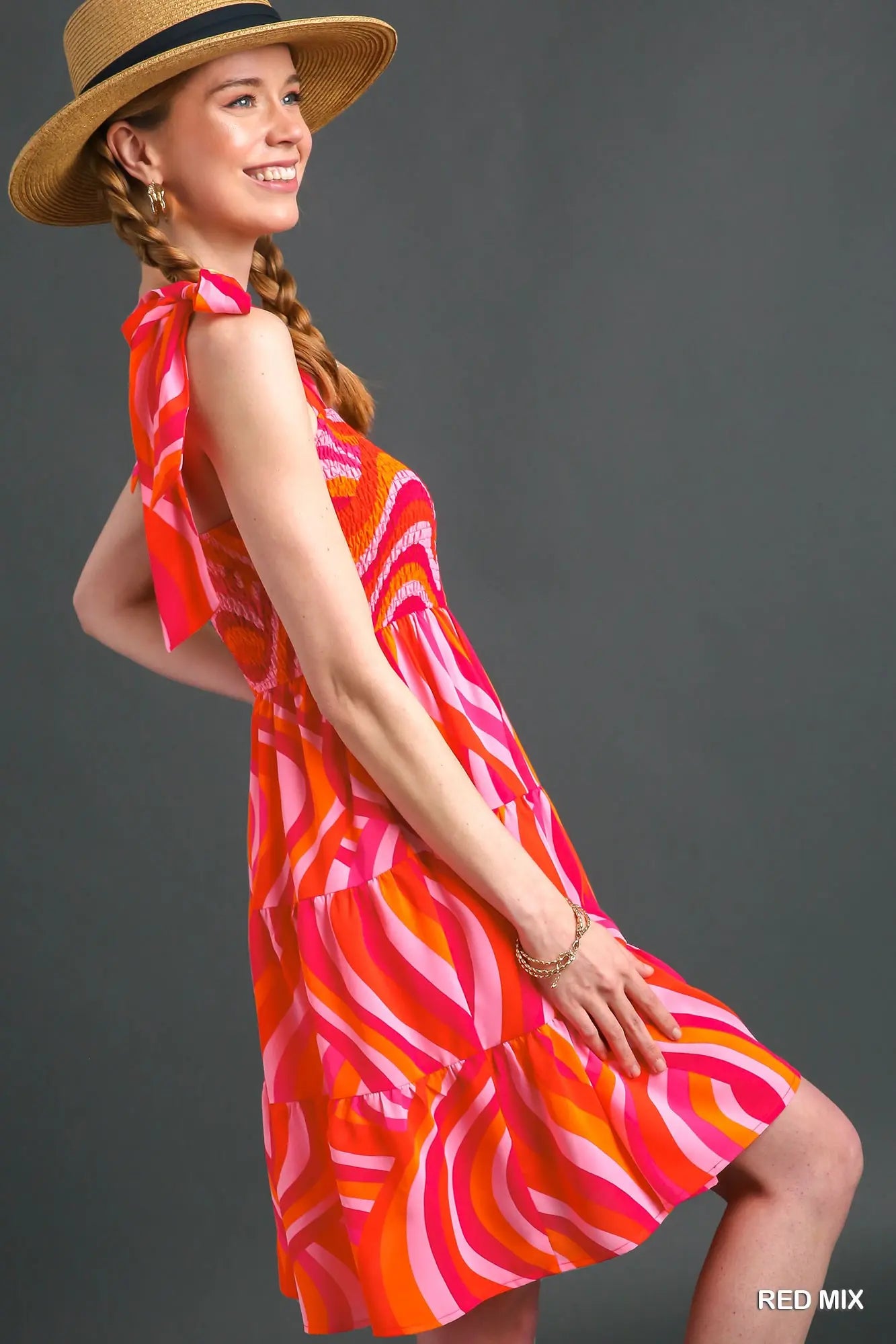 Woman wearing a colorful dress and straw hat on a gray background