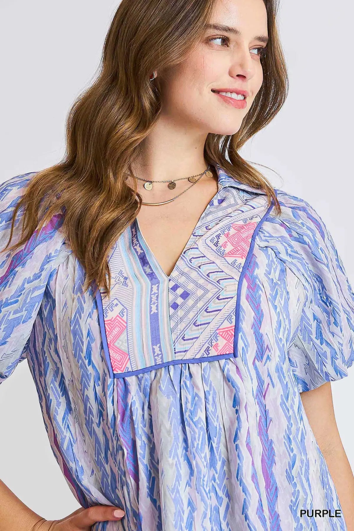 Woman wearing a colorful patterned shirt with a plain background