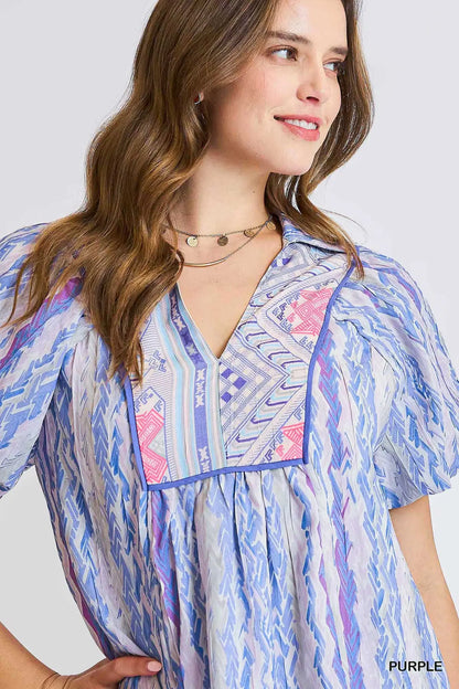 Woman wearing a colorful patterned shirt with a plain background