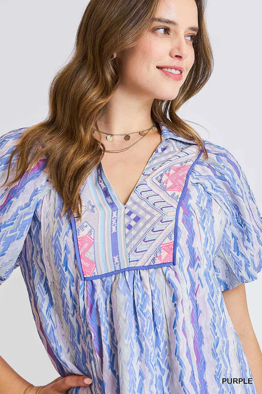 Woman wearing a colorful patterned shirt with a plain background