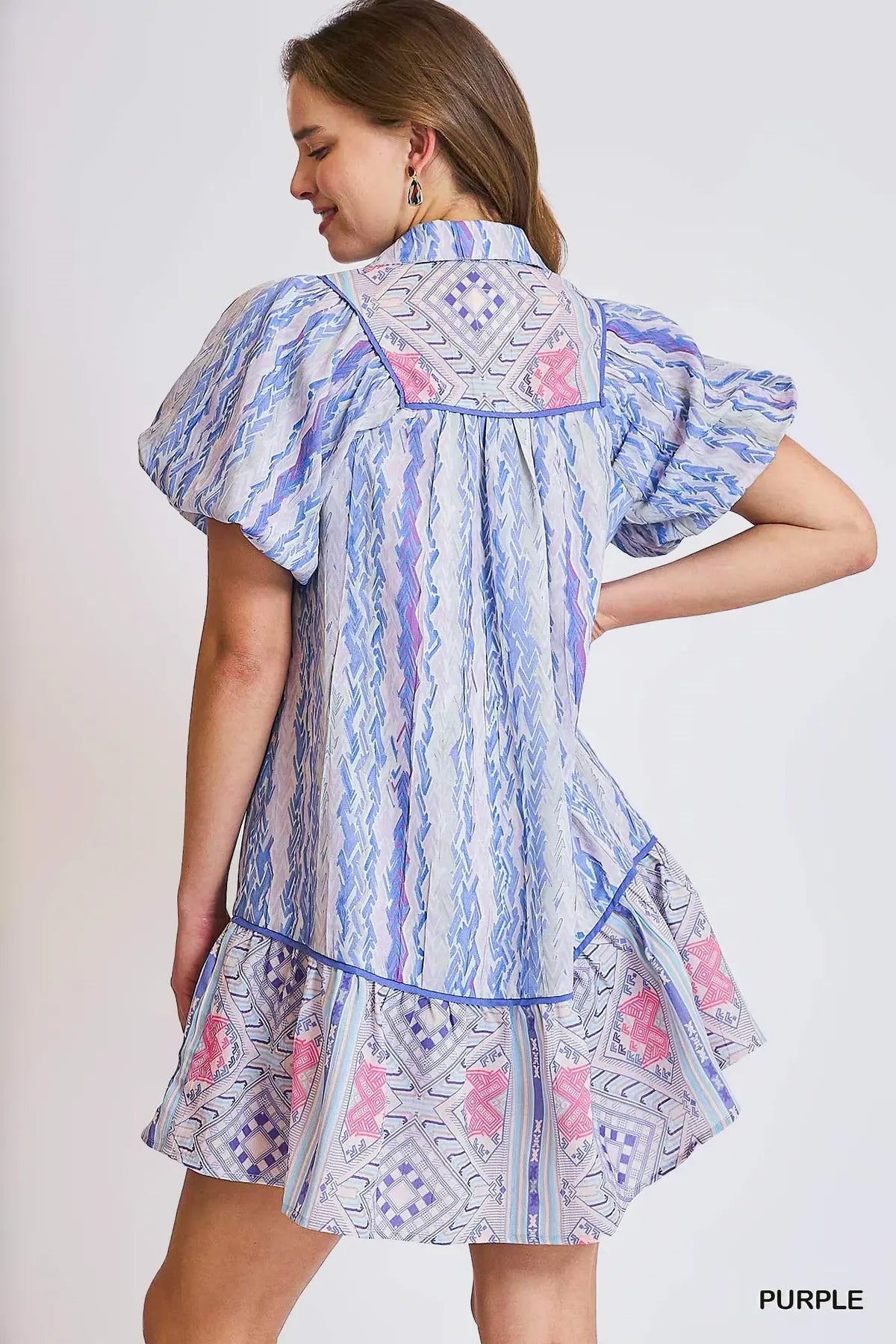 Woman wearing a patterned dress with ruffled sleeves on a white background
