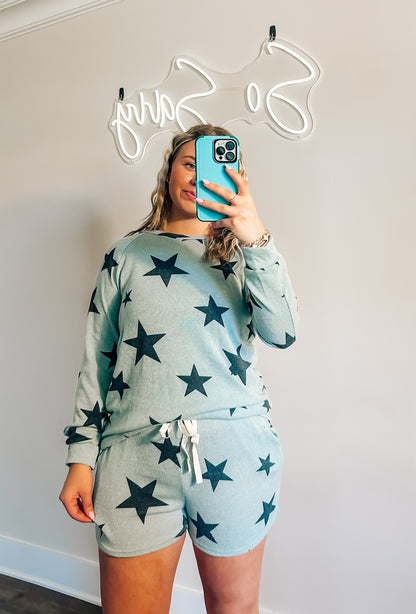 A person wearing a two-piece star-patterned set, with a light blue top and shorts, against a neutral background.