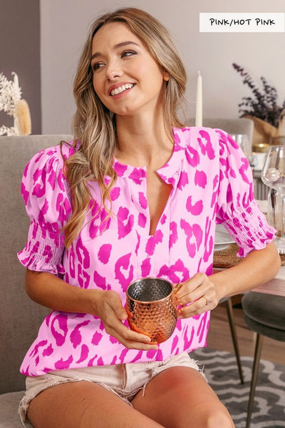Woman wearing a pink leopard print top sitting on a couch holding a copper mug.