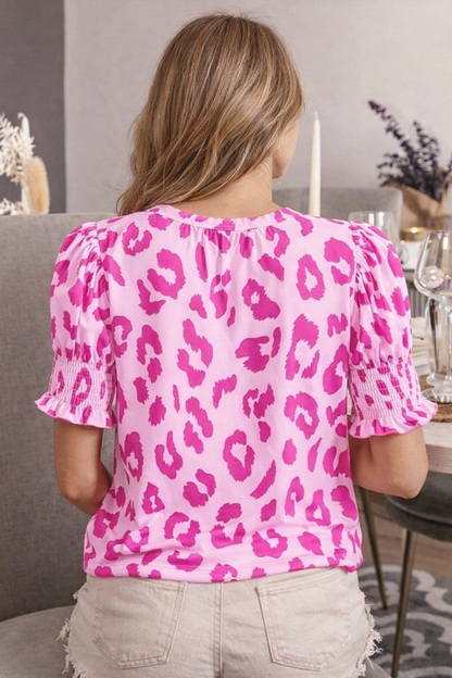 Person wearing a pink leopard print top in an indoor setting