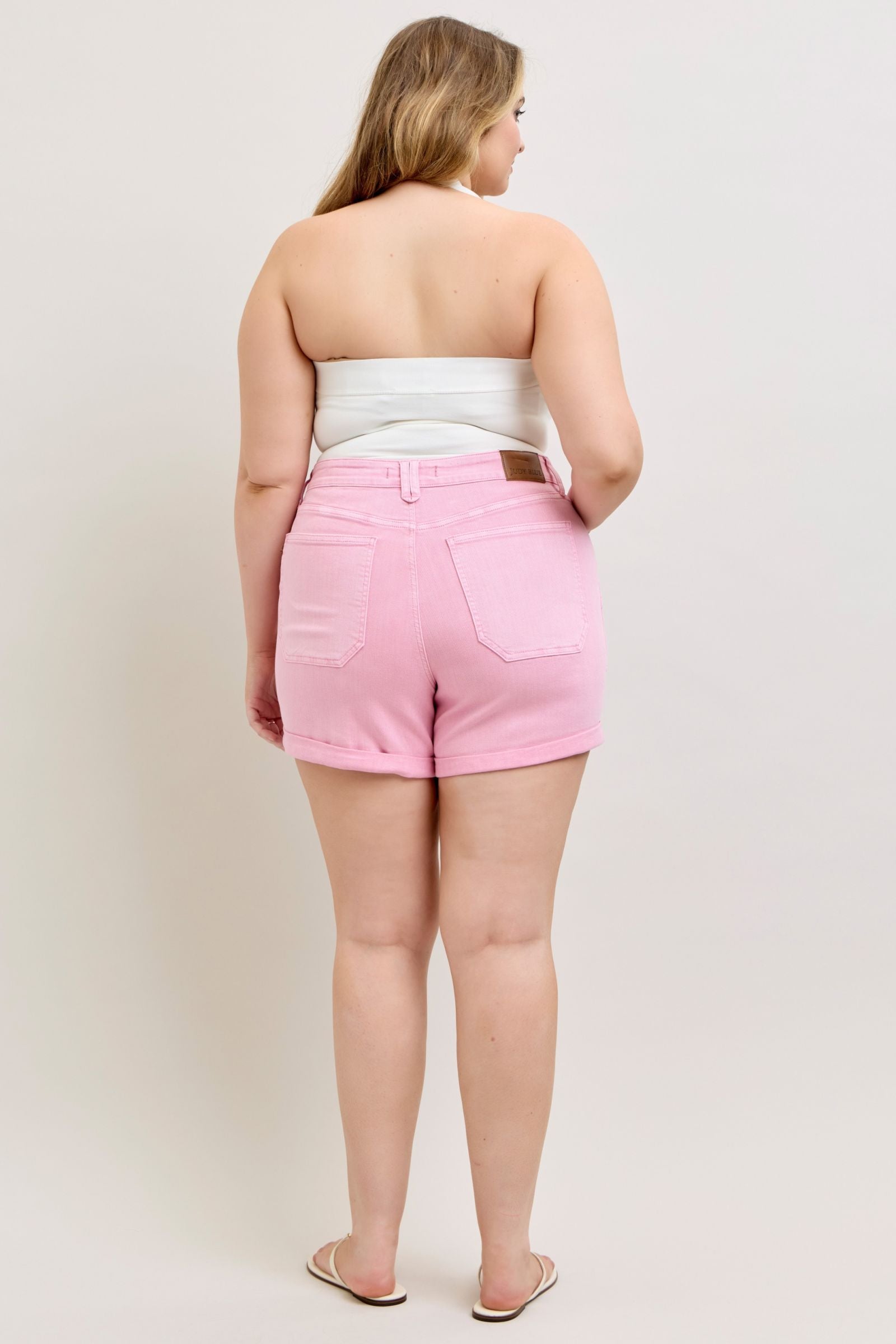 Person wearing pink shorts and a white top on a plain background