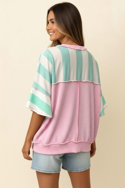 Woman wearing a striped shirt with pink and green colors on a beige background
