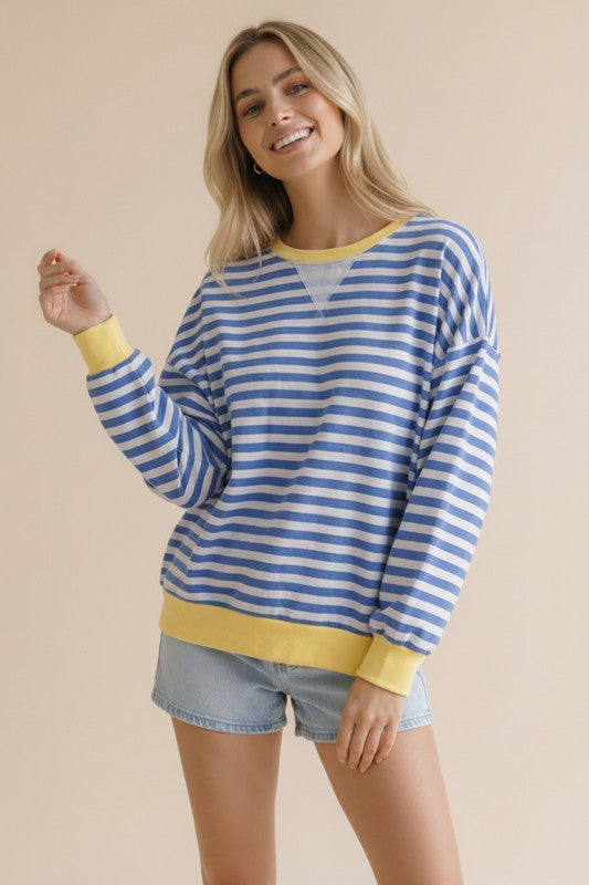 Woman wearing a blue and white striped sweater with yellow accents on a beige background