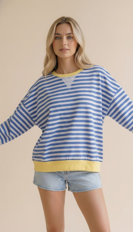 Woman wearing a blue and white striped sweater with yellow accents on a beige background