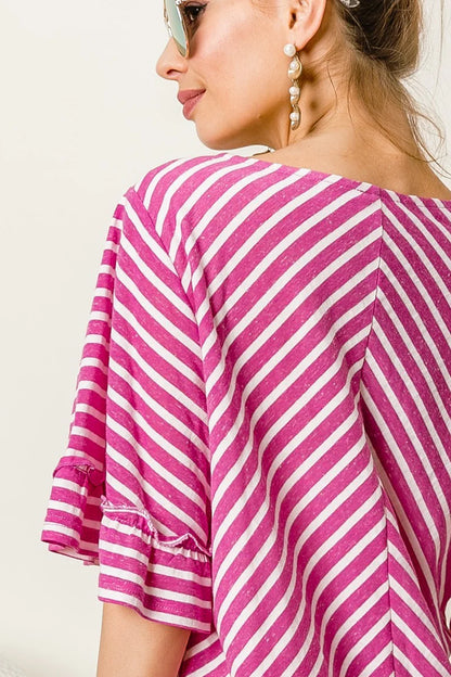 Woman wearing a pink and white striped shirt with a neutral background