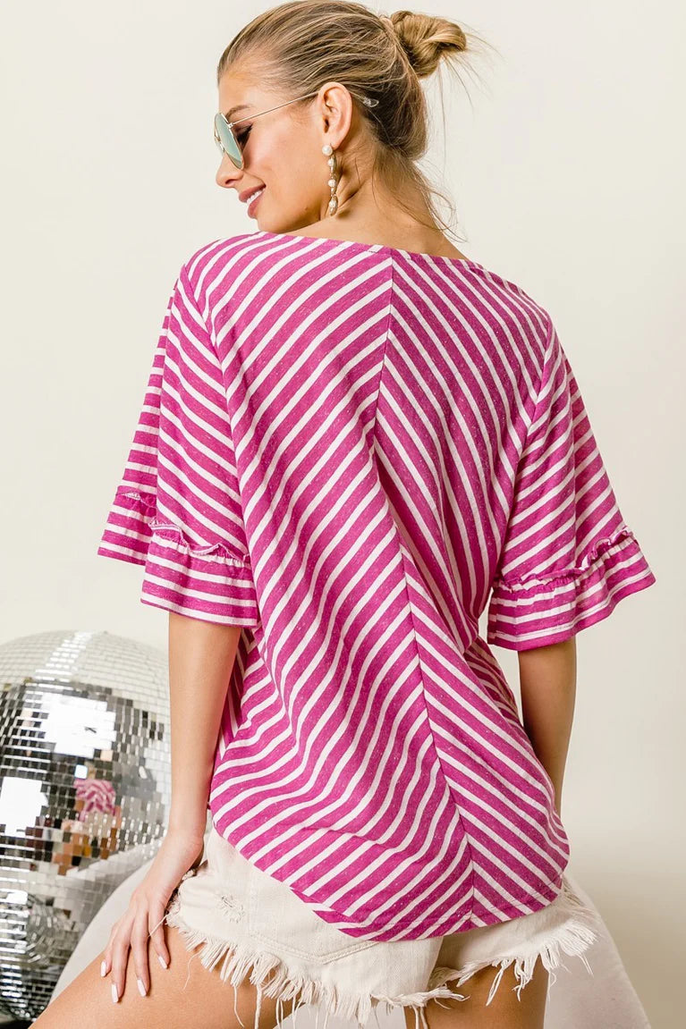 Woman wearing a pink and white striped shirt with a disco ball in the background