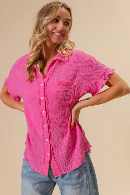 Woman wearing a bright pink button-up shirt and jeans on a beige background
