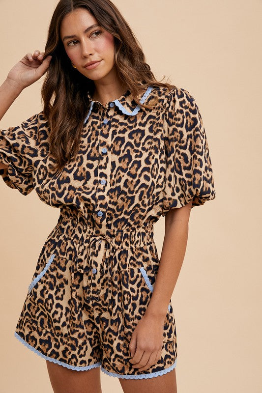 Woman wearing a leopard print romper with lace trim on a beige background