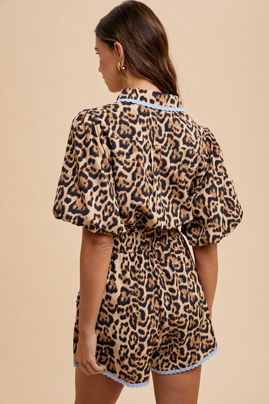 Woman wearing a leopard print romper with lace trim on a beige background