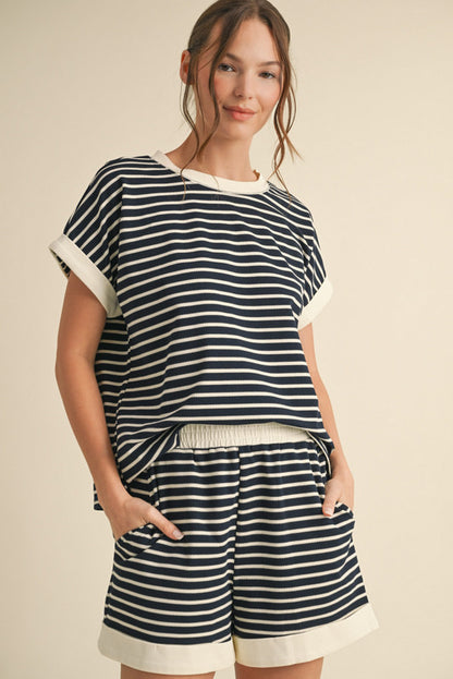 A woman wearing a navy and white striped short-sleeve top with cuffed sleeves and matching elastic waist shorts with pockets.